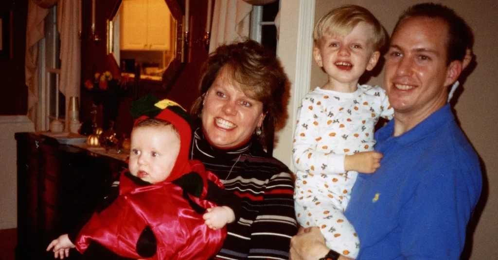 The Woods family indoors with two small children, one in a ladybug costume and the other in Halloween pajamas.