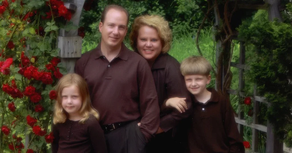 Kim Woods with her husband and two small children standing in a garden of roses.