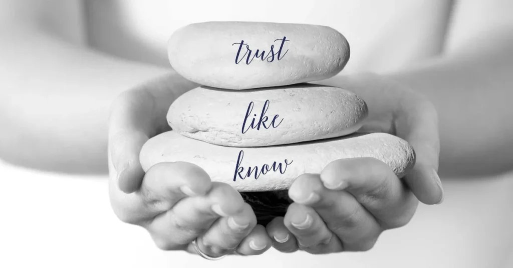 Hands holding three stacked stones labeled 'know,' 'like,' and 'trust.'