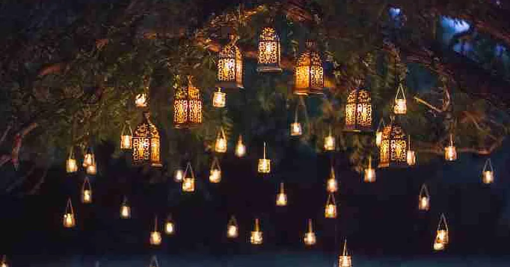 Decorative lanterns hanging from tree branches, glowing warmly in the night.