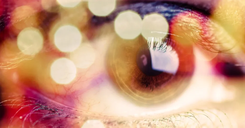 Close-up of an eye with colorful reflections and bokeh light effects.