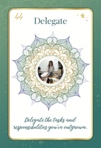 Card from Kim Woods' oracle card deck titled 'Delegate,' featuring a woman leading a team discussion, centered within an intricate mandala design. The card's message reads, 'Delegate the tasks and responsibilities you’ve outgrown,' symbolizing leadership, empowerment, and efficiency.