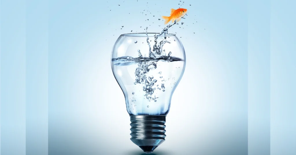 Light bulb filled with water, with a fish jumping out of it.