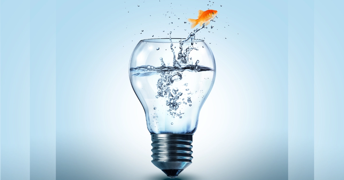 Light bulb filled with water, with a fish jumping out of it.