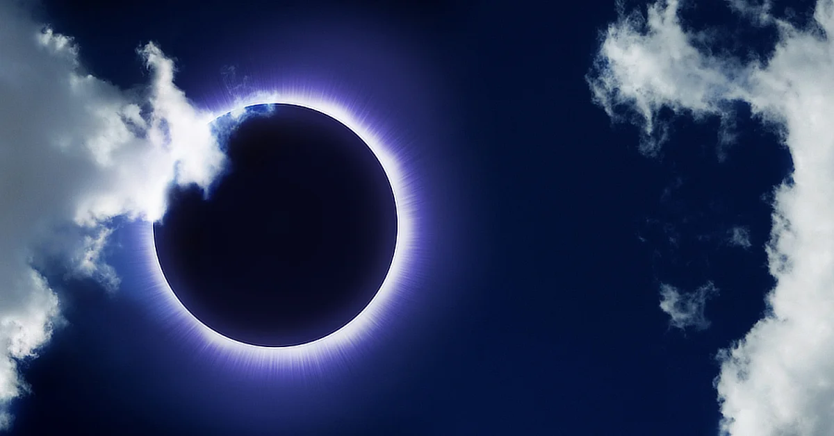 Solar eclipse with the moon covering the sun, surrounded by a glowing corona, partially obscured by clouds.