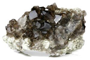 A cluster of smoky quartz crystals, showcasing their dark, translucent appearance with sharp, angular facets. The quartz is embedded in a white rock matrix, highlighting the contrast between the dark crystals and the lighter stone.