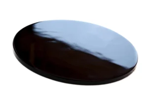 Polished black obsidian crystal disk with a glossy surface, displayed against a white background.