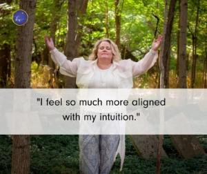 A woman standing outdoors in a wooded area with her arms open and eyes closed, appearing calm and aligned. A client quote is displayed on the image.