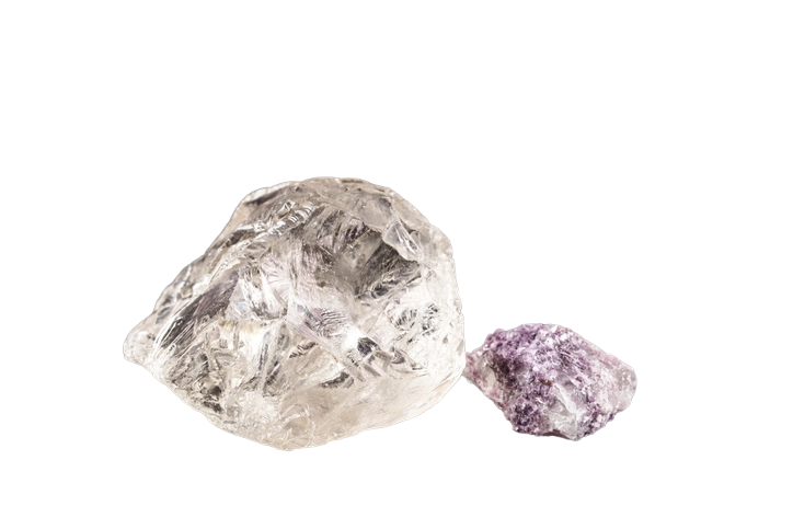 Two raw petalite crystals, clear petalite crystal on the left and a smaller purple petalite crystal on the right.