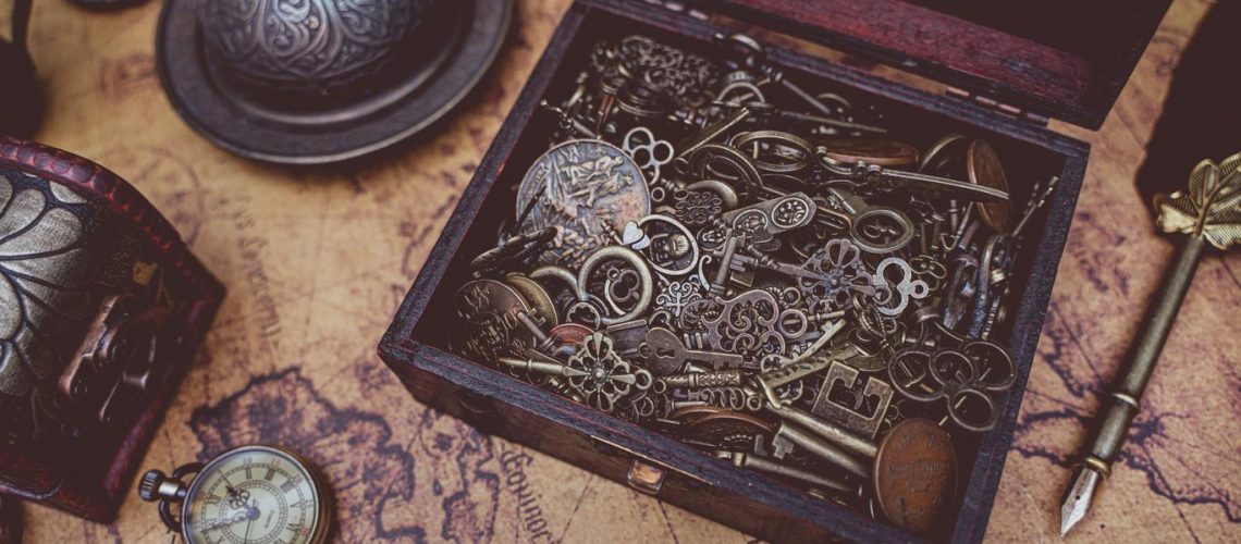 A wooden box filled with antique keys and vintage items on an old map.